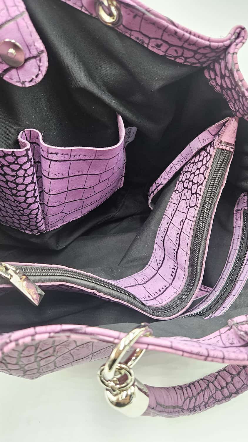 Dettaglio dell'interno della borsa Kali malva con fodera scura e divisorio con zip.